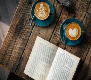 Image of two coffee mugs and a book laying on a table. Representing the benefits that can come from meeting with a dating coach in Houston or Dallas, Texas.
