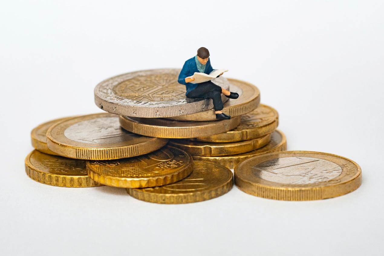 Image figurine of a man sitting on top of a pile of gold coins. Representing the importance of money management that life coaching in Salem, Oregon can help with. With the support of a life coach you can make a money plan that works for you.