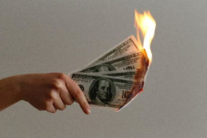 Image of money that is on fire. Showing what life coaching in Oregon can help avoid. With a life coach you can learn money management.